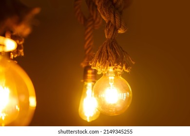 Edison Light Bulb, Vintage Hanging Edison Light Bulb Over Dark Background. Amber Colored Lights With Copy Space Background. 