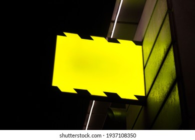 Editable PSD mockup with hanging outdoor glowing sign board at night.