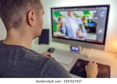 Editing photos in an application program on a desktop computer. A photo of a man from behind working on the preparation of photo and video material for a business partner. Creative work and hobby