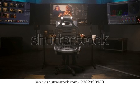 The editor works in studio on computer, edits video, makes color correction for movie post production. Big screens showing color grading program interface with film footage, RGB graphic and levels.