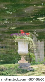 Editorial: ANNEVOIE, BELGIUM, June 17, 2017 - Image of a vase reflected in the water in a pond in the Gardens of Annevoie. The reflection causes soft focus and blur.