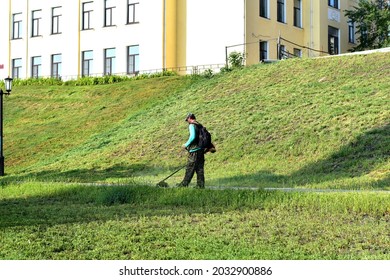 Editorial Image. Tambov. Russia. 08.18.2021. A Worker In A City Park Mows Green Grass In A Park With A Manual Mechanical Scythe.