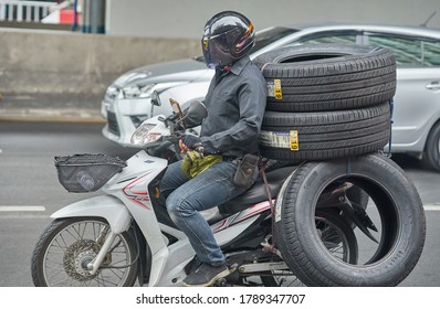 Editorial use only; a motorcycle courier, transporting automobile rubber tires, taken at Bangkok, Thailand, in August 2020.                     