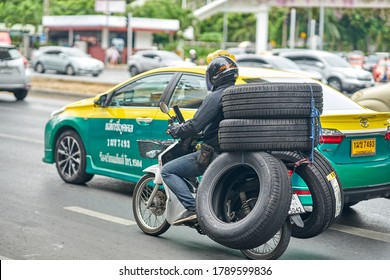 Editorial use only; a motorcycle courier, transporting automobile rubber tires, taken at Bangkok, Thailand, in August 2020.                     