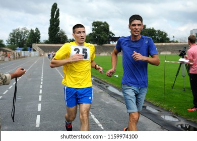 Editorial use only. Runner leading disabled blind athlete (left) by strapped hands. Trials among disabled Ukrainian soldiers to the 43 rd US Marine Corps marathon. July 20, 2018. Kiev, Ukraine