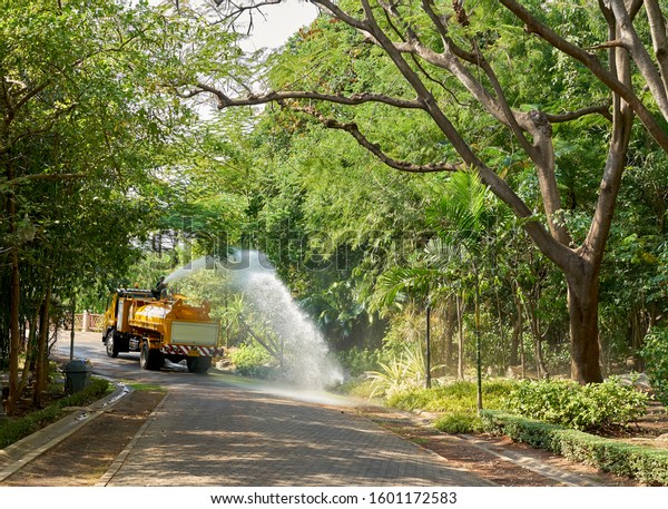Editorial use only; a truck sprays water green trees\
and plants in sunlight, in a park in Bangkok, Thailand, in December\
2019.                      \
