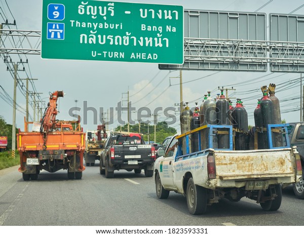 Editorial use only; trucks on a highway driving under an
information sign, taken at Pathumthani, Thailand, in May 2020.     
             