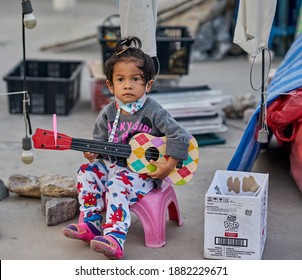 Editorial Use Only; A Young Child Busker Wearing A Face Mask, At A Local Night Market, Taken At Pathumthani, Thailand, On December 25th, 2020.           