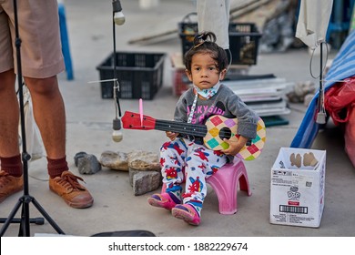 Editorial Use Only; A Young Child Busker Wearing A Face Mask, At A Local Night Market, Taken At Pathumthani, Thailand, On December 25th, 2020.           