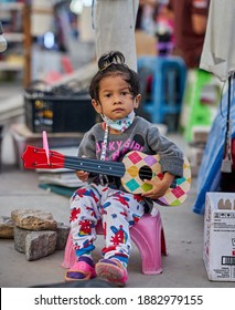 Editorial Use Only; A Young Child Busker Wearing A Face Mask, At A Local Night Market, Taken At Pathumthani, Thailand, On December 25th, 2020.           