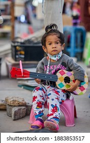 Editorial Use Only; A Young Child Busker Wearing A Face Mask, At A Local Night Market, Taken At Pathumthani, Thailand, On December 25th, 2020.           