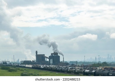 Edmonton, AB, Canada-July 2022; View Over The Sherwood Park Petroleum Coke Calcining Plant And Refinery And In Front Hundreds Of Rail Or Freight Railroad Cars With The City Visible In Haze In Back