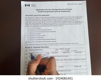 Edmonton, Canada - February 15, 2021: A Black Person Holding A Pen To Complete The Service Canada Application For The Old Age Security Pension And The Guaranteed Income Supplement