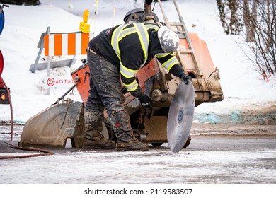 Edmonton, Canada, February 3, 2022: A Contractor Is Taking Off Saw Blade From Diesel Walk-behind Flat Saw Machine In Winter Season Public Work, Snow, Asphalt