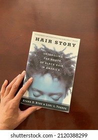 Edmonton, Canada - February 5, 2022: A Black person touching a book called Hair Story: Untangling The Roots of Black Hair in America by Ayana D. Byrd and Lori L. Tharps
