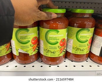 Edmonton, Canada - January 15, 2022: Black Person Reaching For Jars Of Safeway's Compliments Organic Primavera Pasta Sauce On Display On A Grocery Store Shelf