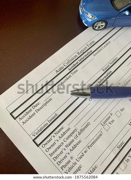 Edmonton, Canada -\
November 1, 2020: An auto collision report form with a pen and a\
blue car in the\
background