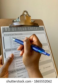 Edmonton, Canada - November 24, 2020: A Black Person Holding A Pen To Complete A Business End Of Year Financial Checklist 