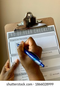 Edmonton, Canada - November 24, 2020: A Black Person Holding A Pen To Complete A Business End Of Year Financial Checklist 