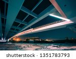 Edmonton Walterdale Bridge shot in the winter at night from underneath. The ice is visible as is the glow from the city and the old Epcor building across the river. Styled in Teal and orange tones.