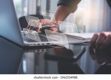 E-document, paperless office concept. Businessman working on laptop computer keyboard with electronics document icons on virtual screen - Shutterstock ID 1962534988