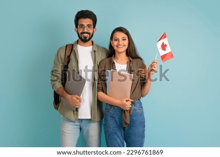 Education abroad, immigration to EU, language school. Cheerful multicultural young arab man and indian woman students with Canadian flag, books and laptop on blue background