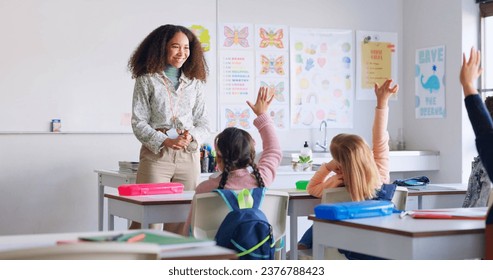 Education, answer and teacher with boy in classroom for learning, discussion and knowledge. Help, studying and hands raised with children and woman at school for why, scholarship and questions - Powered by Shutterstock