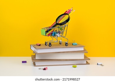 Education, Back To School. Shopping Cart With Supplies Near Pile Of Books.