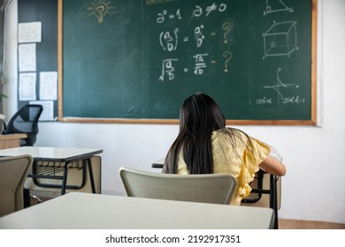 Education  Back view school girl lesson in classroom write hardworking blackboard  primary child is sitting lessons at table in school writing drawing in notebook  Back to school concept