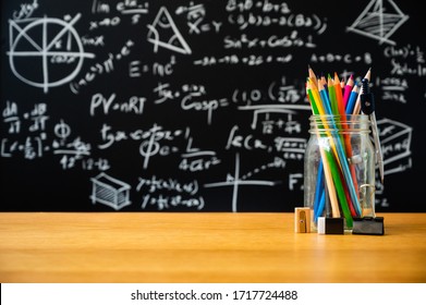 Education Background Concept. Stationery In Glass Jar Color Pencil, Compasses Tool On Chalkboard With The Mathematical Formula Background.