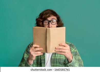 Education Concept. Amazed Young Man With Glasses Reading Book On Color Background