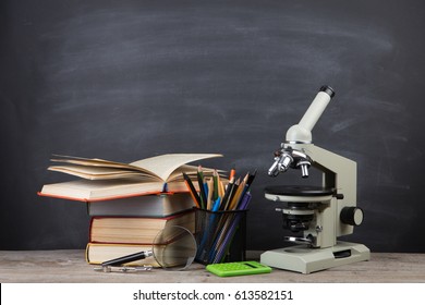 Education concept - books and microscope on the desk in the auditorium