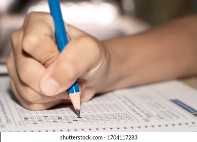 Education concept, exams of examination kid use pencil lead on hand student holding to make answer on multiple choice of question exam paper in classroom school, kids background for learning concept