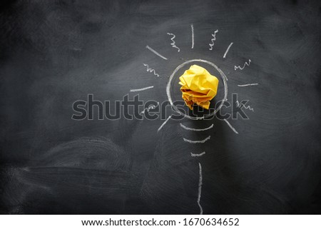 Education concept image. Creative idea and innovation. Crumpled paper as light bulb metaphor over blackboard