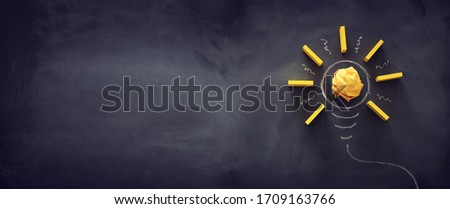 Education concept image. Creative idea and innovation. Crumpled paper as light bulb metaphor over blackboard