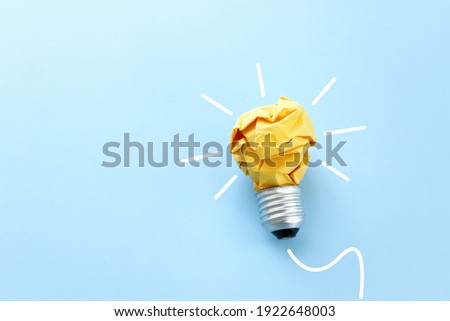 Education concept image. Creative idea and innovation. Crumpled paper as light bulb metaphor over blue background