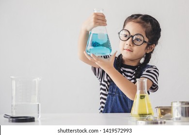 Education concept - Little scientists children is looking at erlenmeyer flask containing chemicals to perform experiments in the laboratory, Beaker on the side table. - Powered by Shutterstock