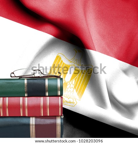 Education concept - Stack of books and reading glasses against National flag of Egypt
