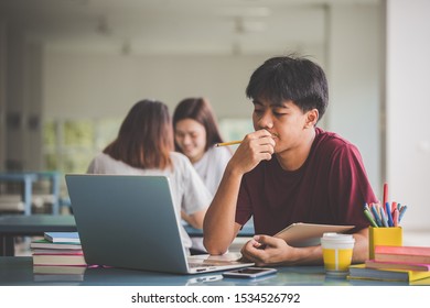 Education concept - Students using laptop and learning online at university. Teens and modern technology. Young man reading a book on notebook screen for final exam.