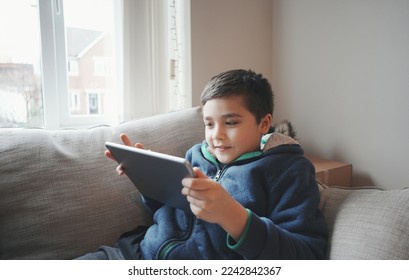 Education concept,School Kid holding tablet reading E-book for homework,Portrait happy Child playing game online on internet with friends,Young boy watching cartoon on digital pad,Kid sitting on sofa - Powered by Shutterstock