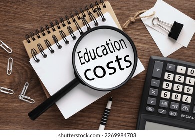 Education costs . wooden background with text on magnifier glass. two notepads and a calculator - Shutterstock ID 2269984703