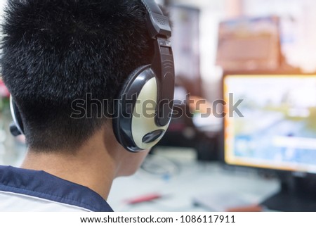 Education e-learning foreign languages Concept : Asian Student Young man wearing Headphones listening English songs music and searching for learning abroad in computer pc at classroon of university