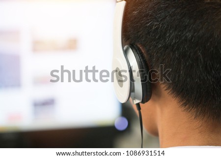 Education e-learning foreign languages Concept : Student Young man wearing Headphones listening English songs music and searching for learning abroad in classroon of university