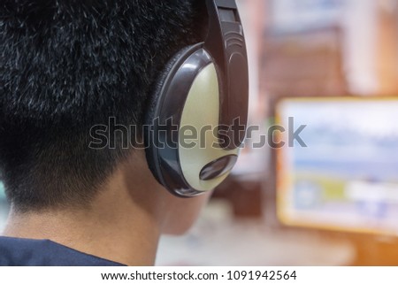 Education e-learning foreign languages Concept : Asian Student Young man wearing Headphones listening English songs music and searching for learning abroad in computer pc at classroon of university
