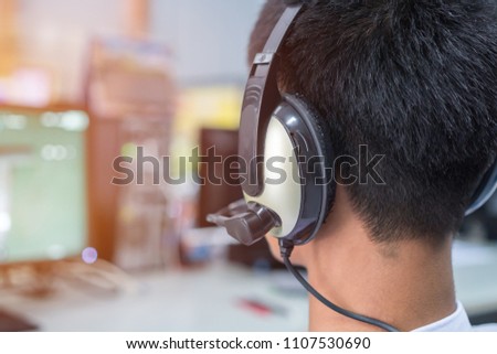 Education e-learning foreign languages Concept : Asian Student Young man wearing Headphones listening English songs music and searching for learning abroad in computer pc at classroon of university
