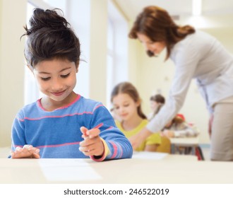 Bildungs-, Grundschulen- und Kinderkonzept - glückliche kleine Schülerin mit Stift und Papier auf Unterricht und Lehrerhintergrund