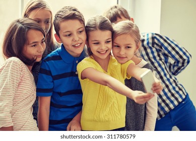 education, elementary school, drinks, children and people concept - group of school kids taking selfie with smartphone in corridor - Powered by Shutterstock