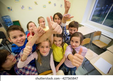 Education, Elementary School, Learning, Gesture And People Concept - Group Of School Kids And Showing Thumbs Up In Classroom