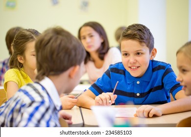 Education, Elementary School, Learning And People Concept - Group Of School Kids Talking During Lesson In Classroom