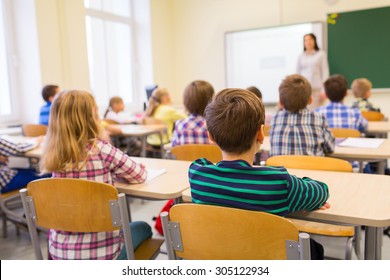 Bildung, Grundschule, Lernen und Menschen Konzept - Gruppe der Schulkinder, die im Klassenzimmer sitzt und Lehrer anhört